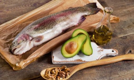 fish, avocado, walnuts laid out on a wooden board