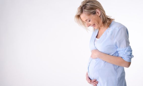 Image of a happy pregnant woman wearing a blue shirt