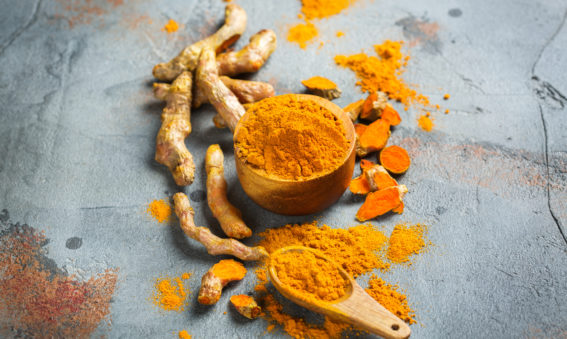 Raw organic orange turmeric root and powder, curcuma longa on a grunge cooking table.