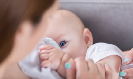 A lady with blue nail polish breastfeeding a baby