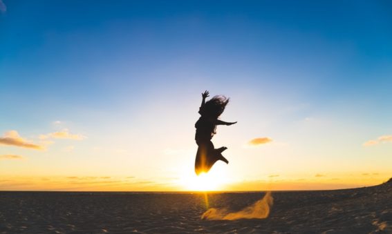 Woman jumping in the air with a sunset behind her